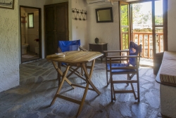 talbe with 2 chairs, single bed and doors to the balcony.